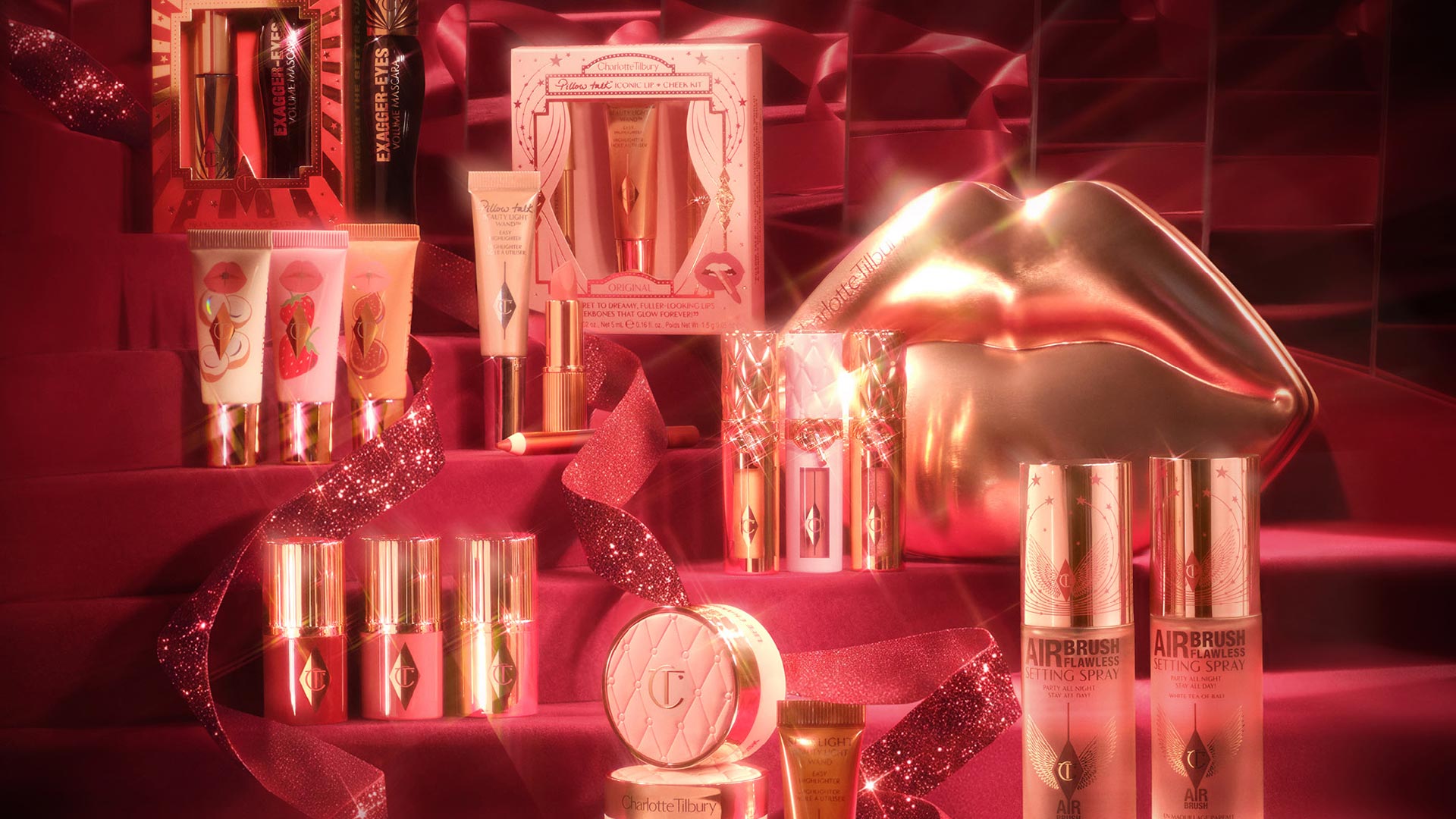 Luxury beauty gift sets including lip glosses, setting sprays, powders and mascaras in coral and rose gold tones with golden packaging and sparkling ribbons