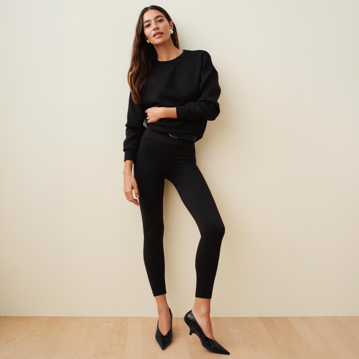 Woman wearing black sweatshirt and black ankle-length leggings with black kitten heels