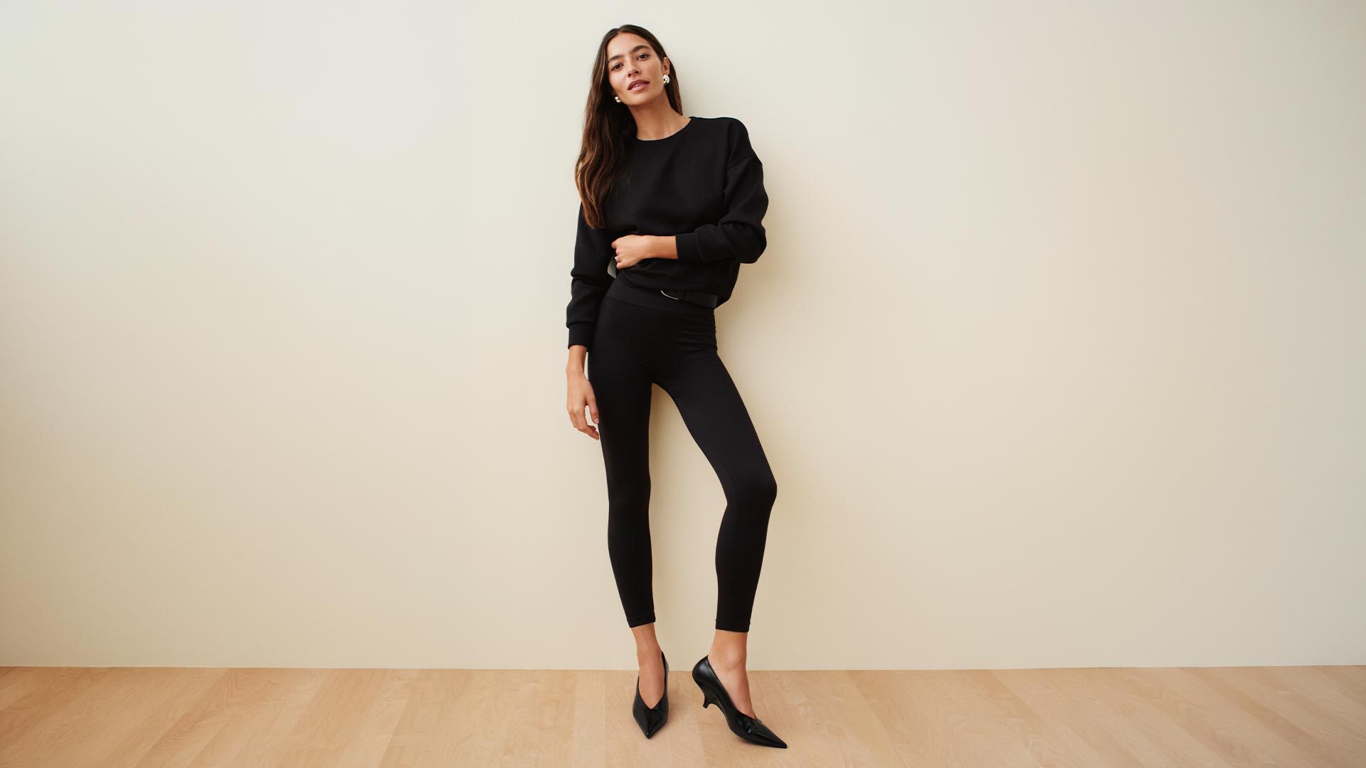 Woman wearing black sweatshirt and black ankle-length leggings with black kitten heels