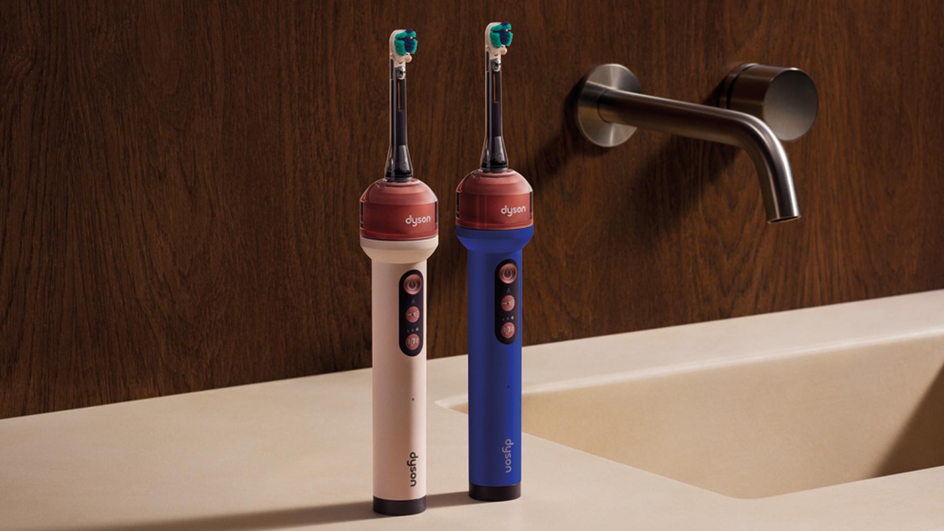 Two Dyson electric toothbrushes in cream and blue with teal brush heads positioned on bathroom sink