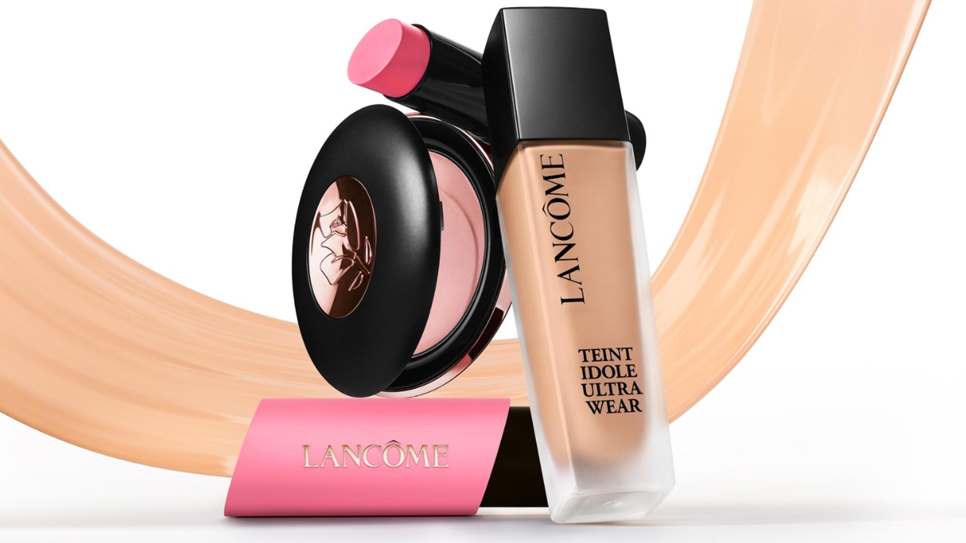 Lancôme Teint Idole Ultra Wear foundation and Blush Subtil powder with pink lipstick, displayed with beige brush strokes.