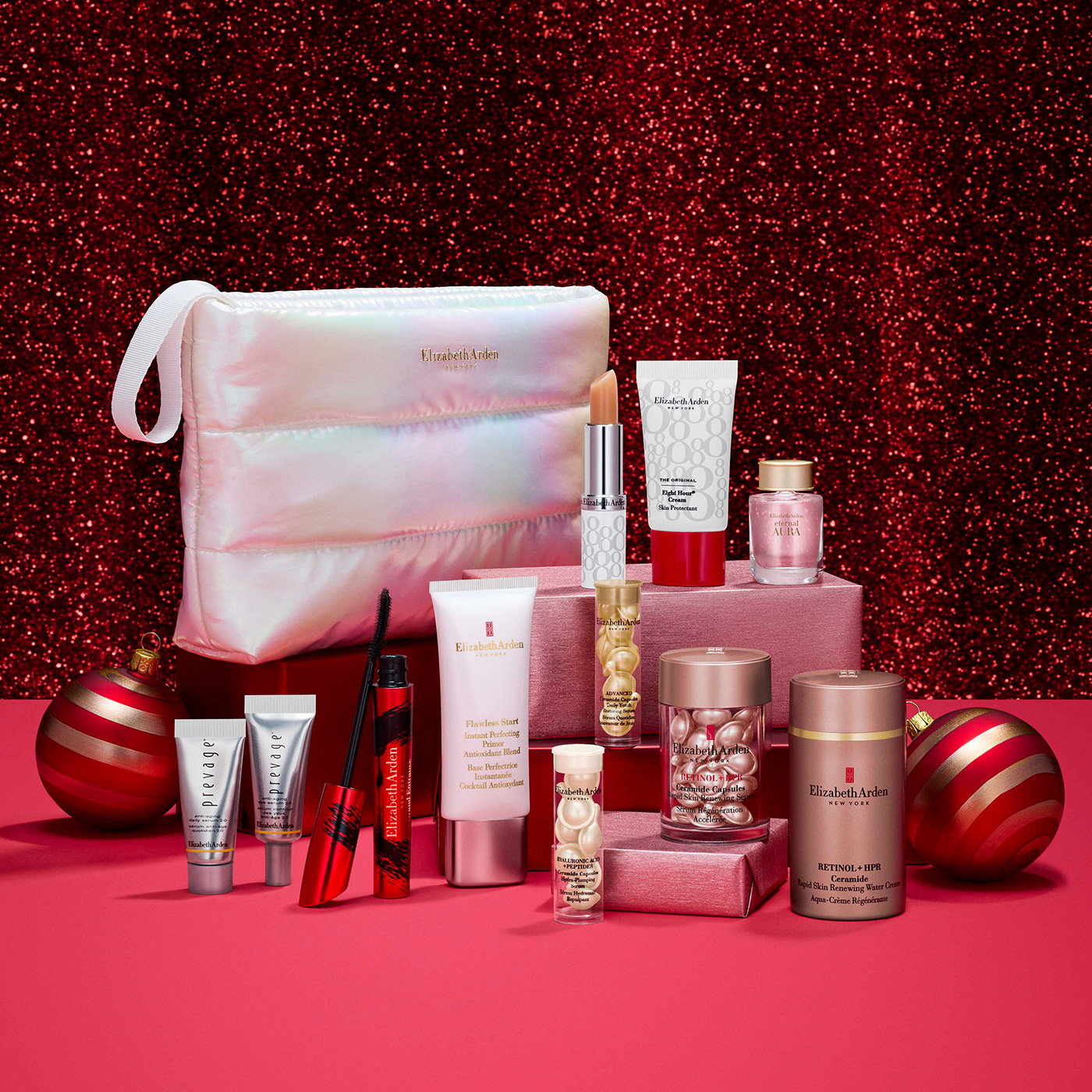 Elizabeth Arden beauty gift set with padded cosmetics bag, skincare creams, lipstick, mascara and perfume on red glitter background