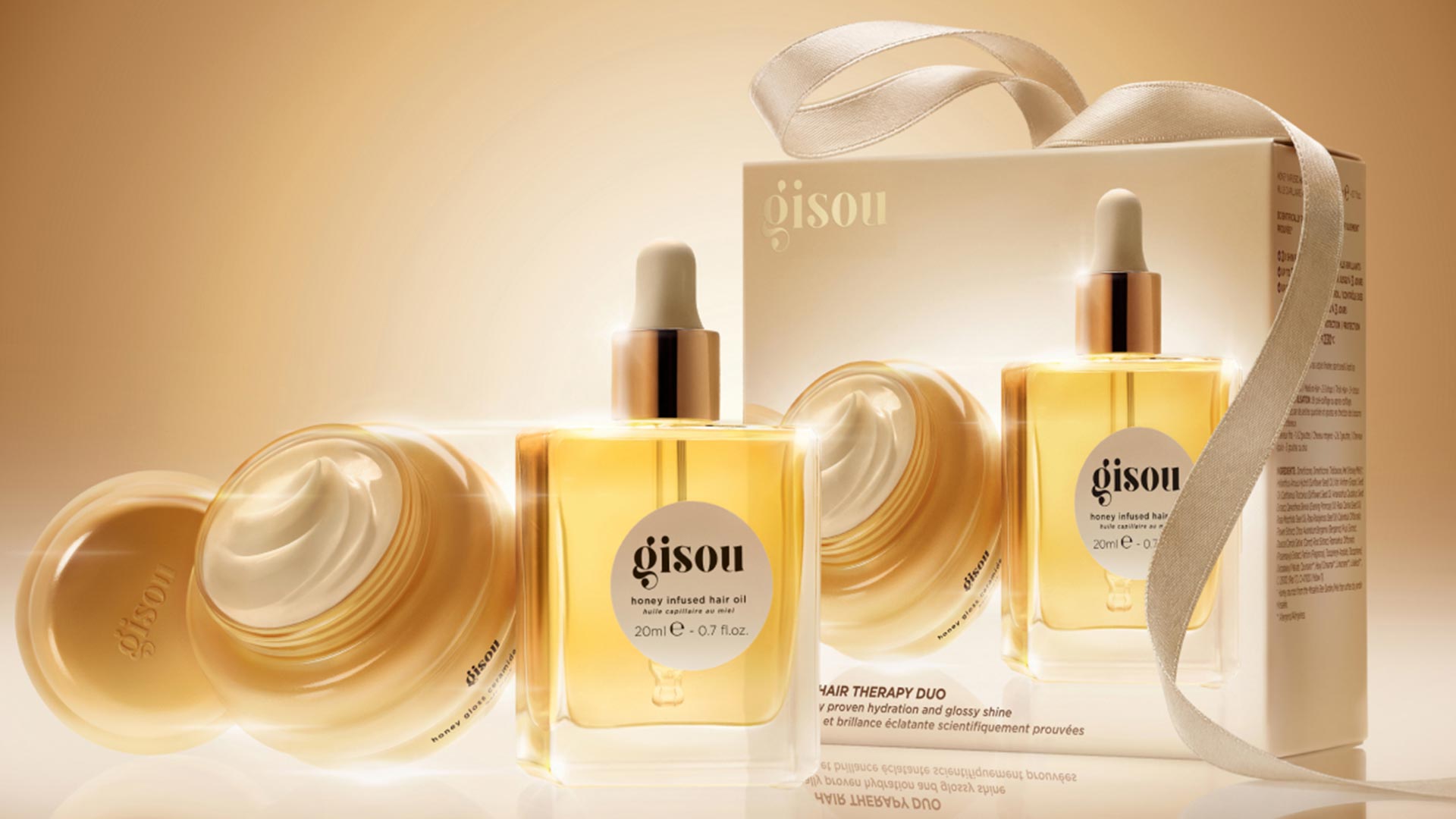 Gisou honey-infused hair oil gift set with cream jar, golden oil bottles, and beige ribbon box