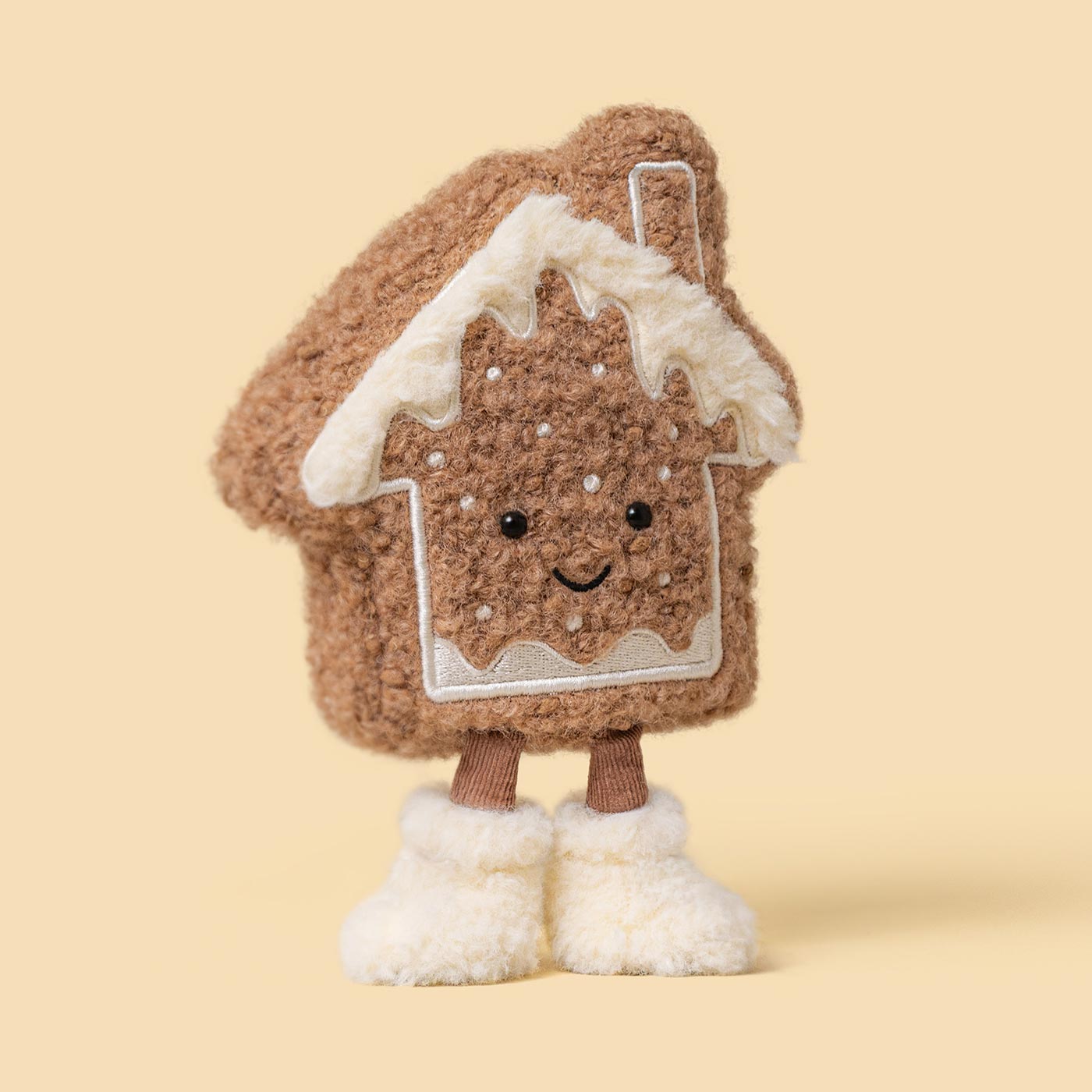 Plush gingerbread house character with white icing detail and smiling face