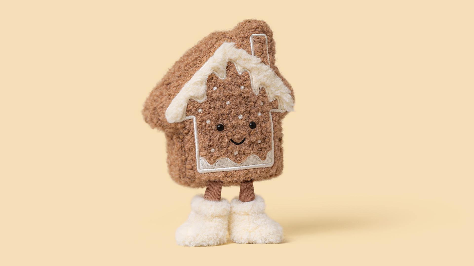 Plush gingerbread house character with white icing detail and smiling face