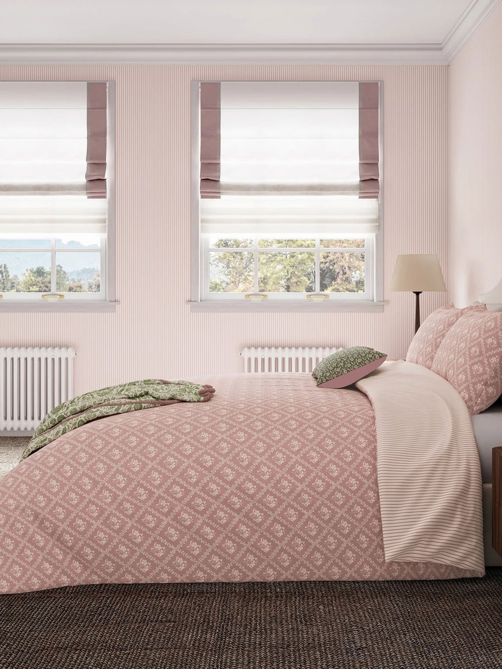 Cozy bedroom with pink bedding, two windows, soft lighting, and a floral wall decoration. Neutral and calming color palette.