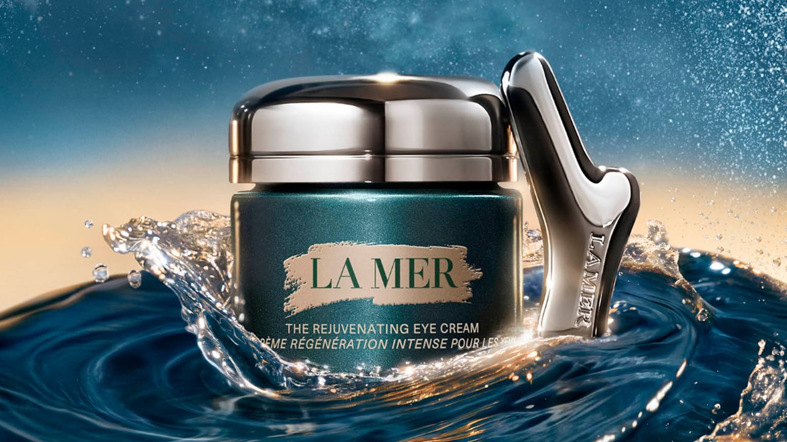 La Mer rejuvenating eye cream jar with a metallic applicator, set amidst splashing water.
