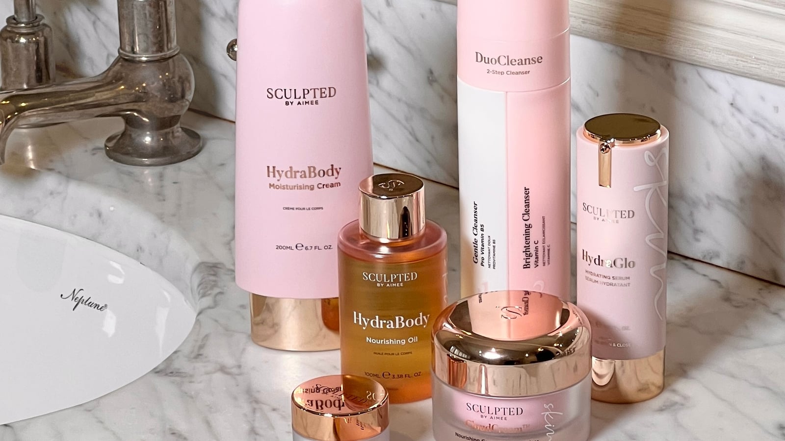 A collection of skincare products on a marble countertop near a sink.