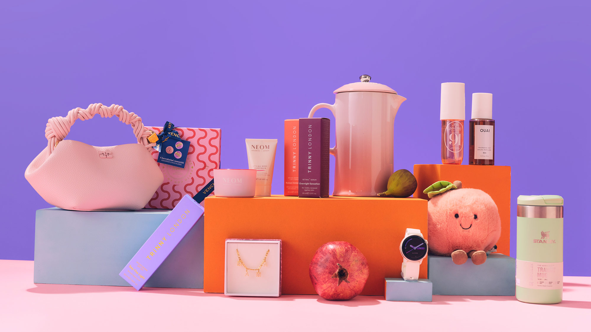 A colorful arrangement of assorted items, including a handbag, watch, cosmetics, and plush toy, displayed against a purple background.