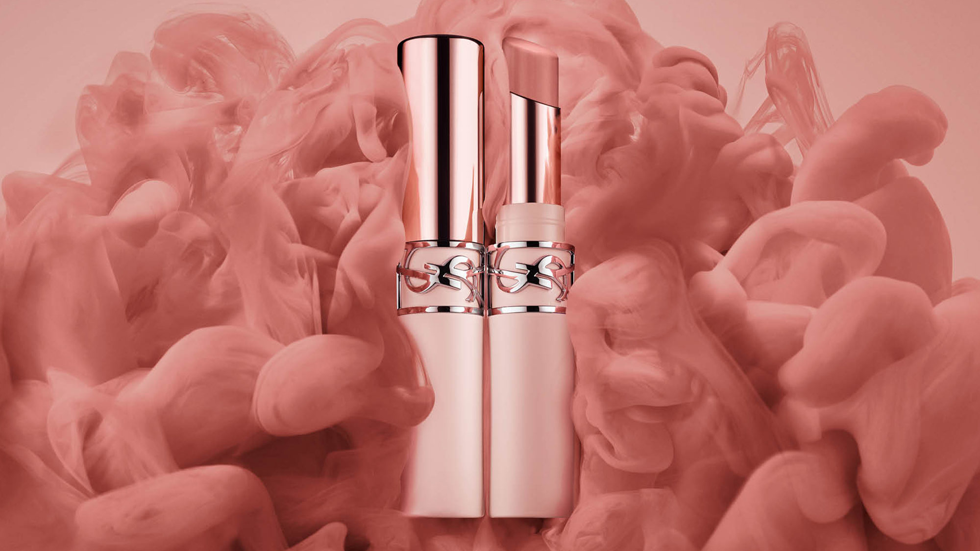 Two elegant lipstick tubes stand amidst swirling pink smoke.