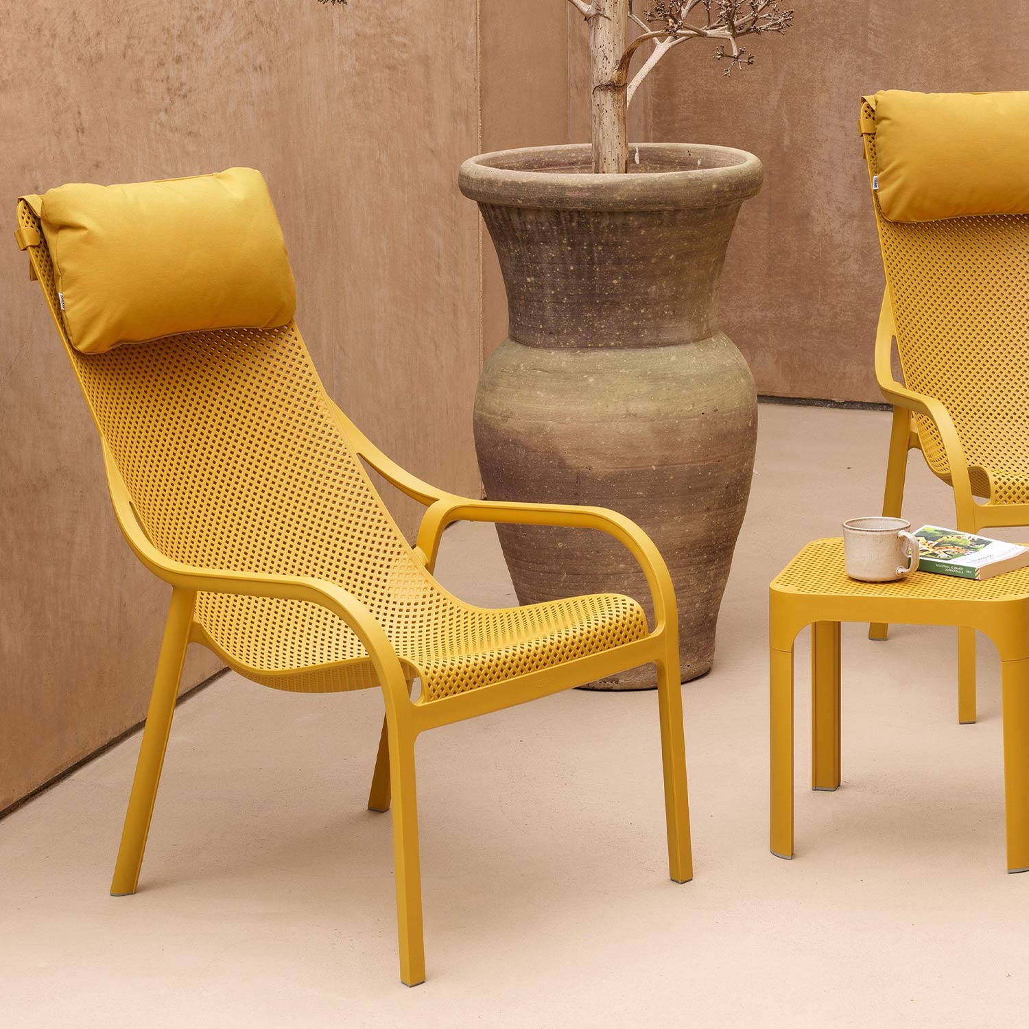 Two yellow mesh garden chairs with cushions and small side table in outdoor setting