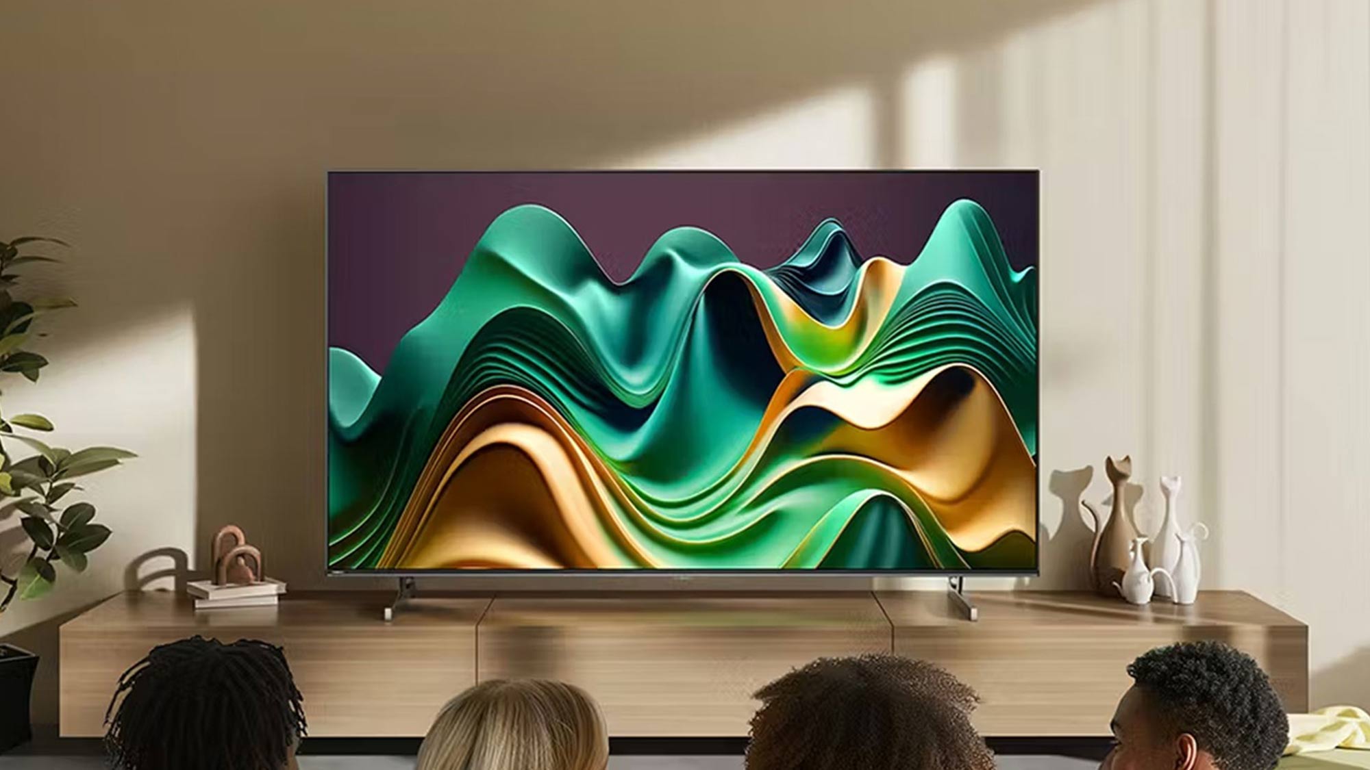 Four people watching a Hisense TV displaying flowing waves in teal, green and gold colours on a wooden media console