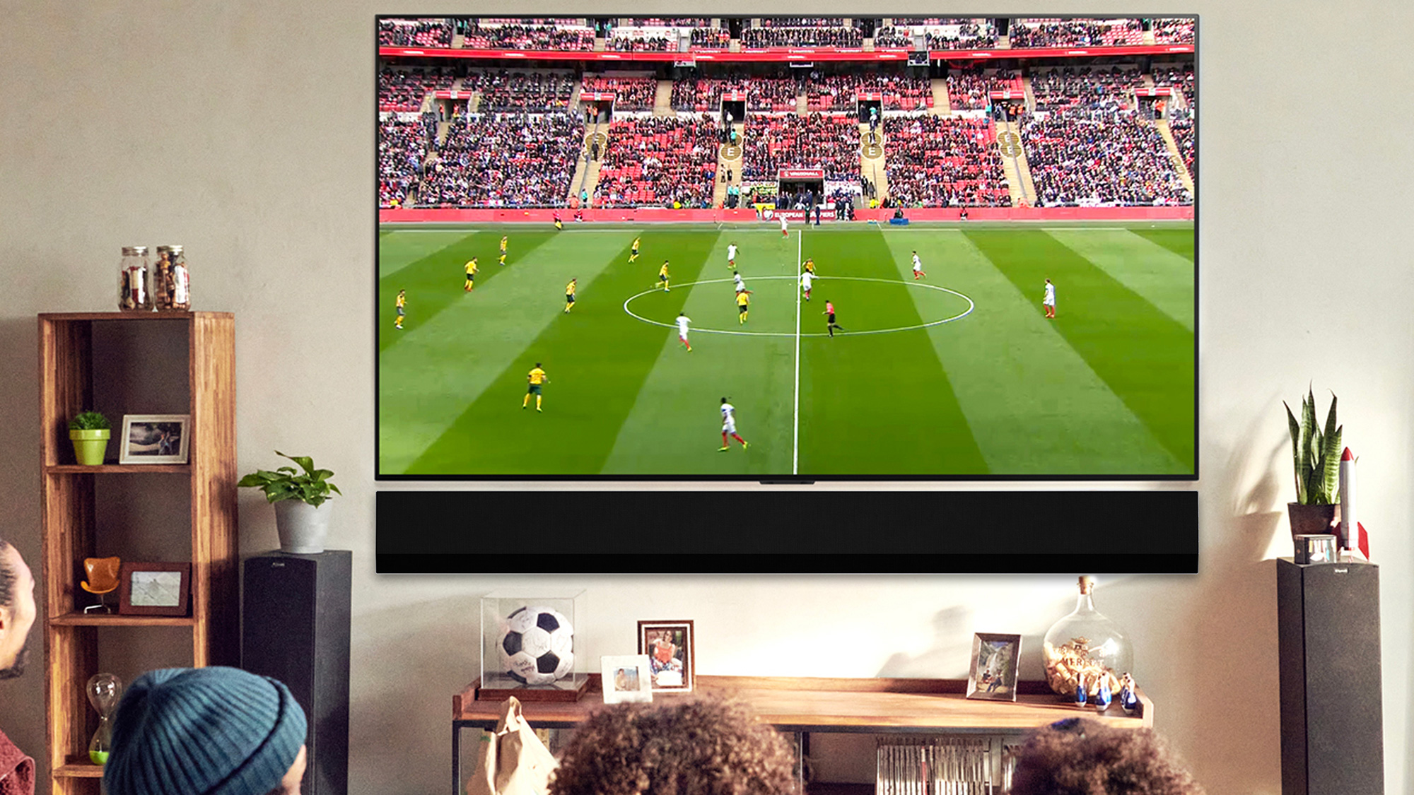 Large television displaying a live football match with packed stadium, set in a modern living room