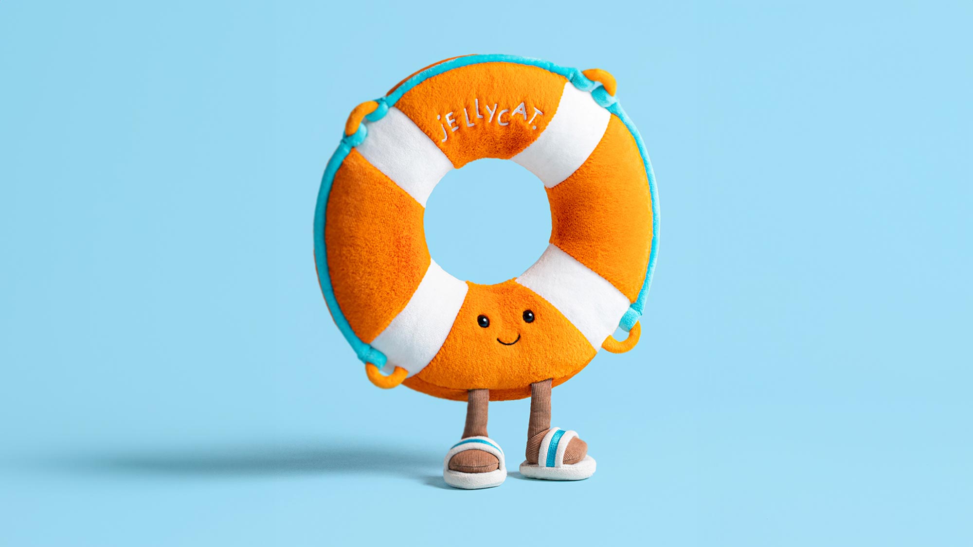 Orange and white plush life ring toy character with smiling face and outstretched arms against light blue background