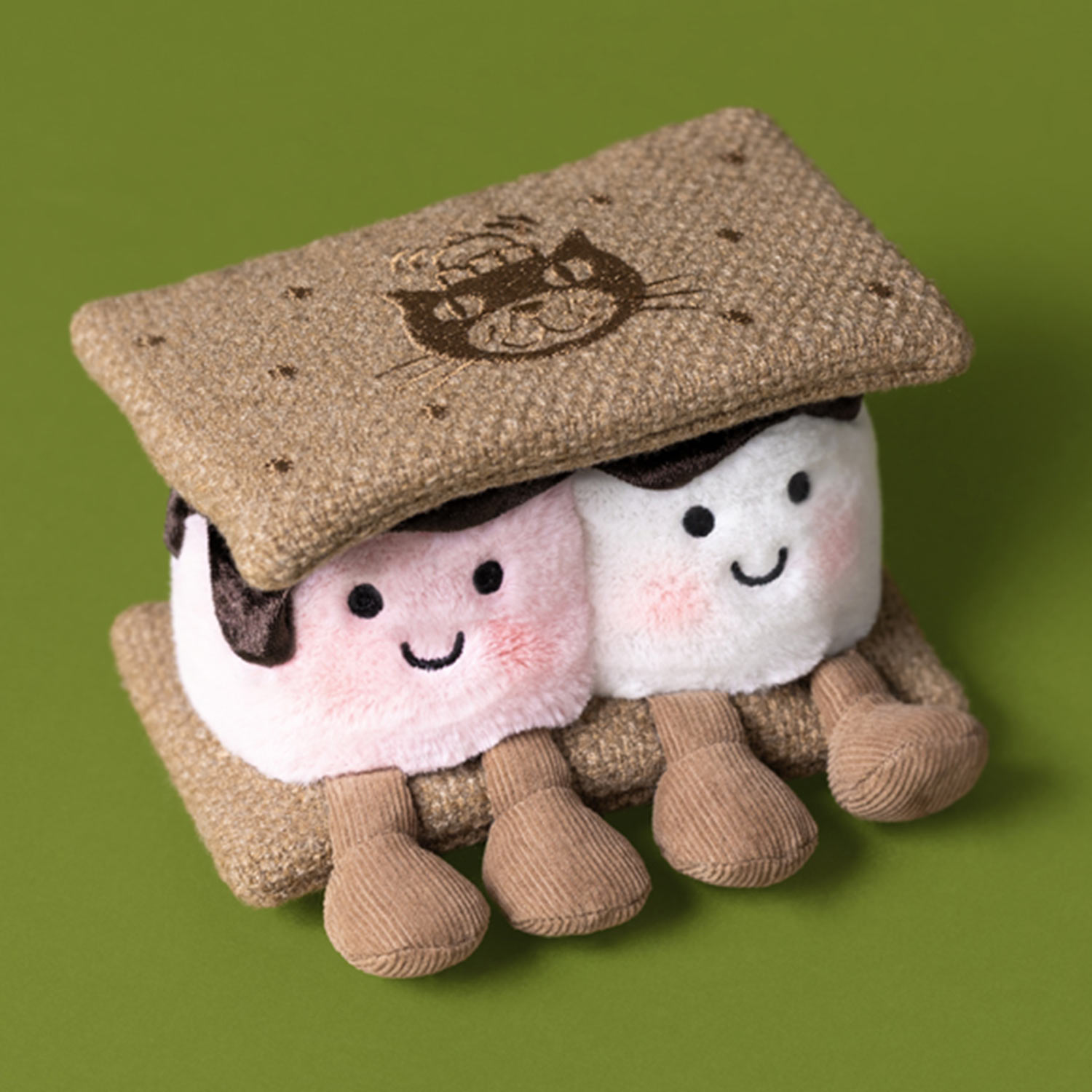 Two cute Jellycat plush toys wearing knitted hats against green background