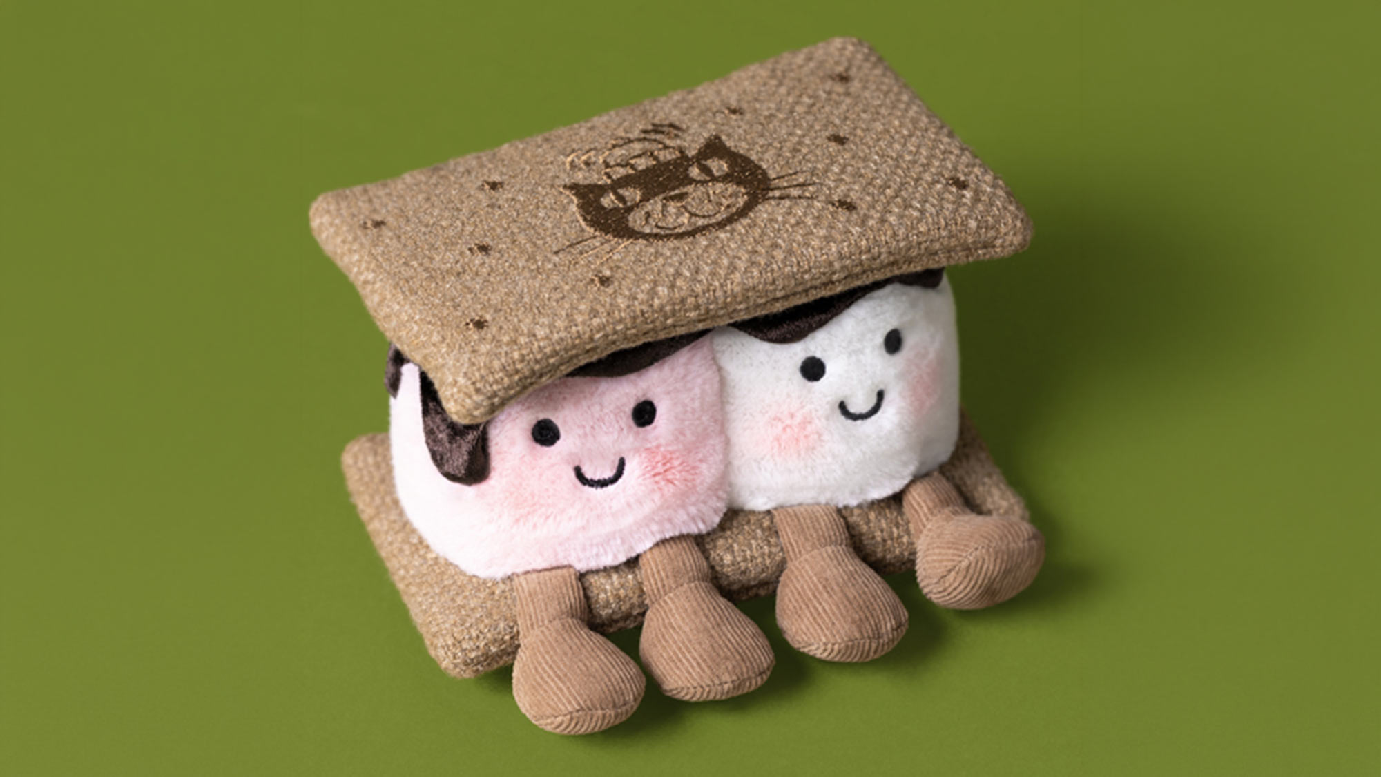 Two cute Jellycat plush toys wearing knitted hats against green background