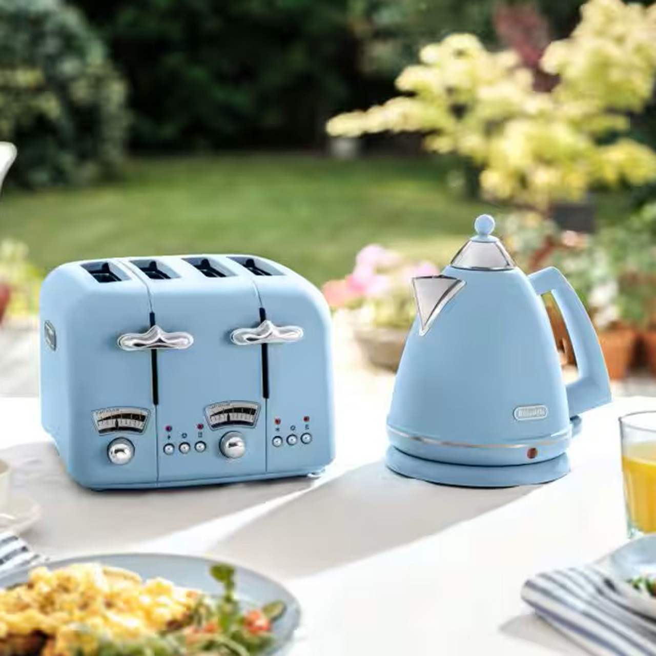 Light blue toaster and kettle on garden table with breakfast items and morning beverages