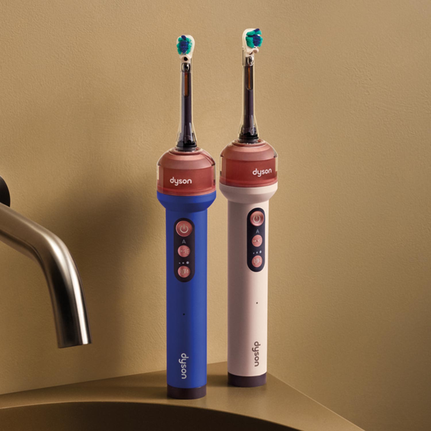 Dyson Camerajet electric toothbrushes in blue and white displayed next to modern black wall-mounted tap and basin fixtures