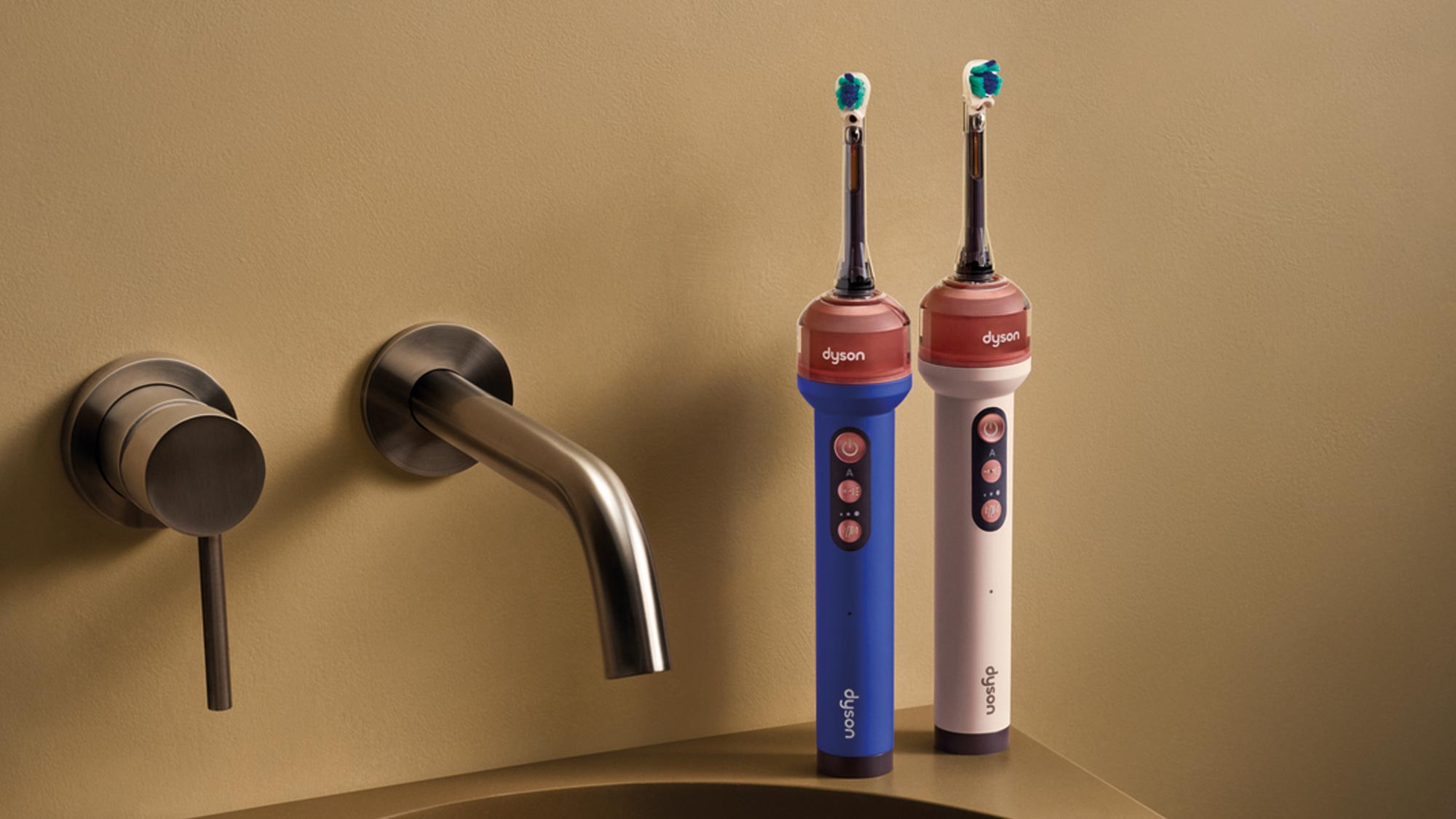 Dyson Camerajet electric toothbrushes in blue and white displayed next to modern black wall-mounted tap and basin fixtures