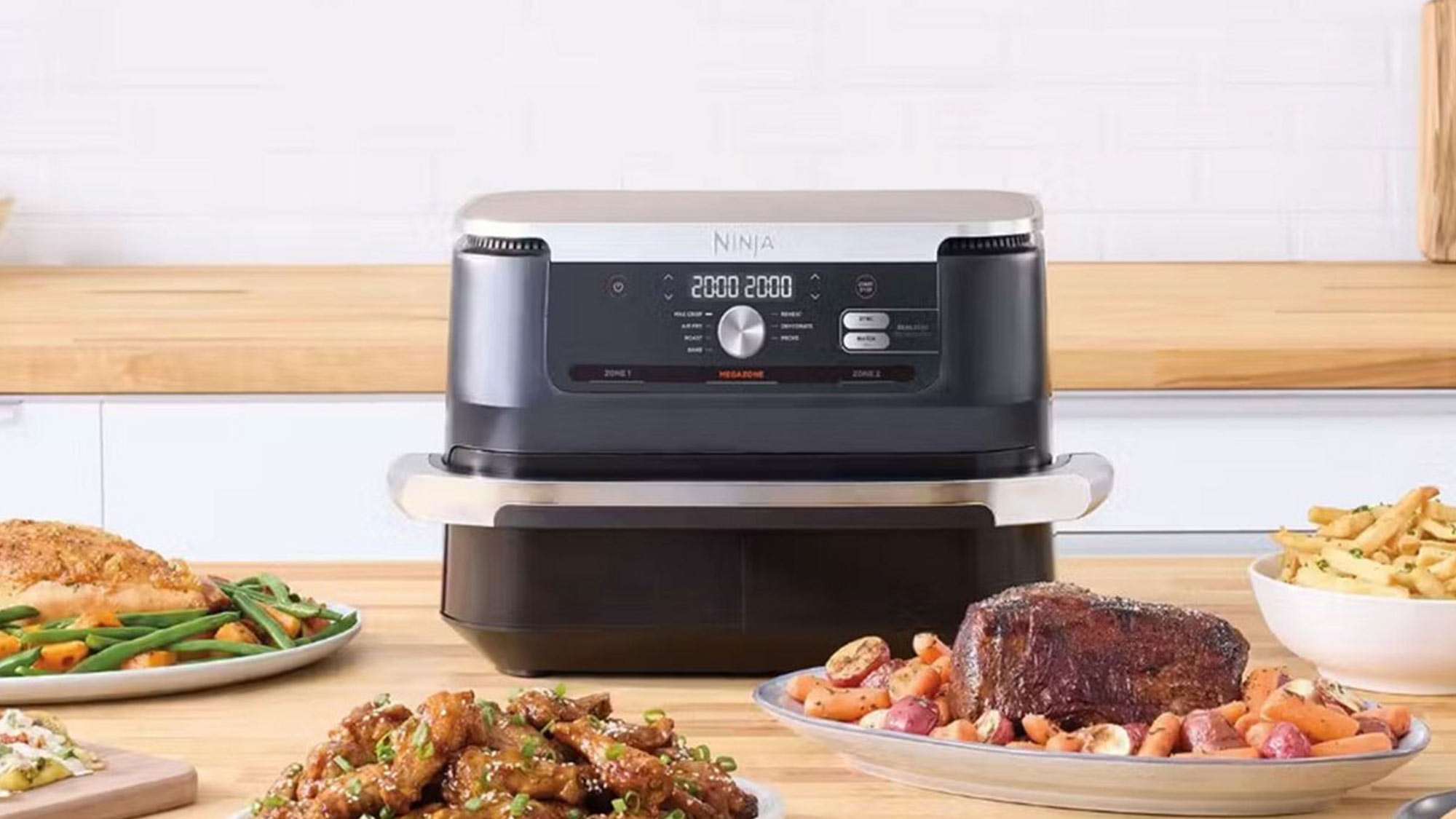 A kitchen with a Ninja appliance surrounded by various cooked dishes, including meat and vegetables, on a wooden countertop.