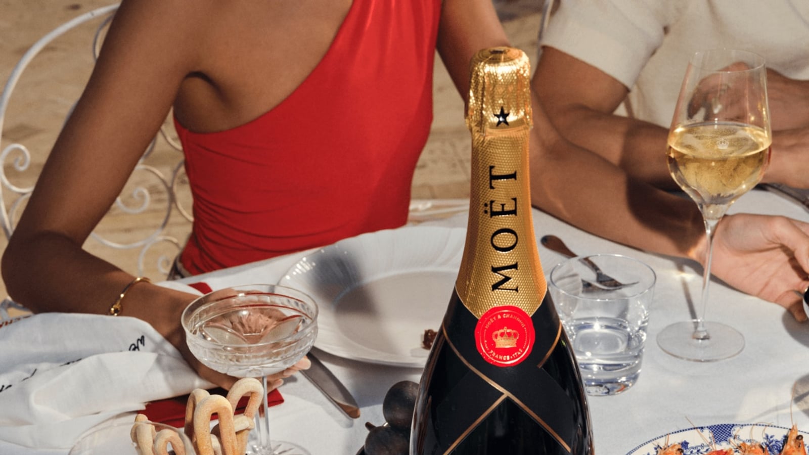 Table with Moët & Chandon champagne, caviar, shrimp, breadsticks, and glasses at a gathering.