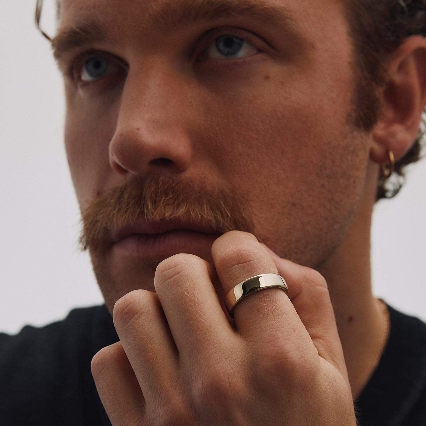 Man wearing polished gold Oura Ring on finger, demonstrating wellness tracking technology
