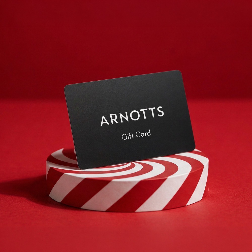 Black gift card displayed on red and white striped cylindrical stand against red background