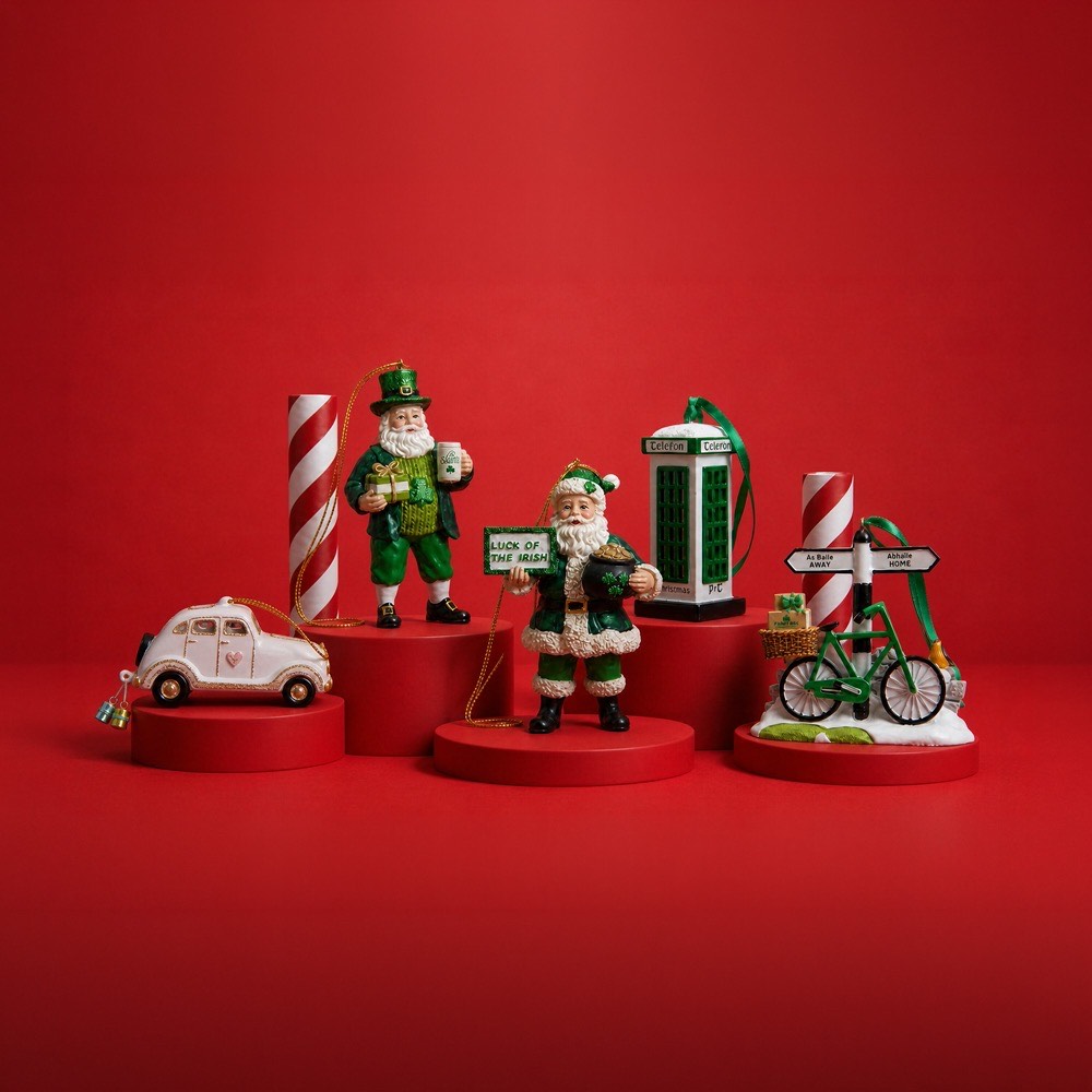Irish-themed Christmas decorations including leprechaun figures, lucky signage, toy car and bicycle on red background