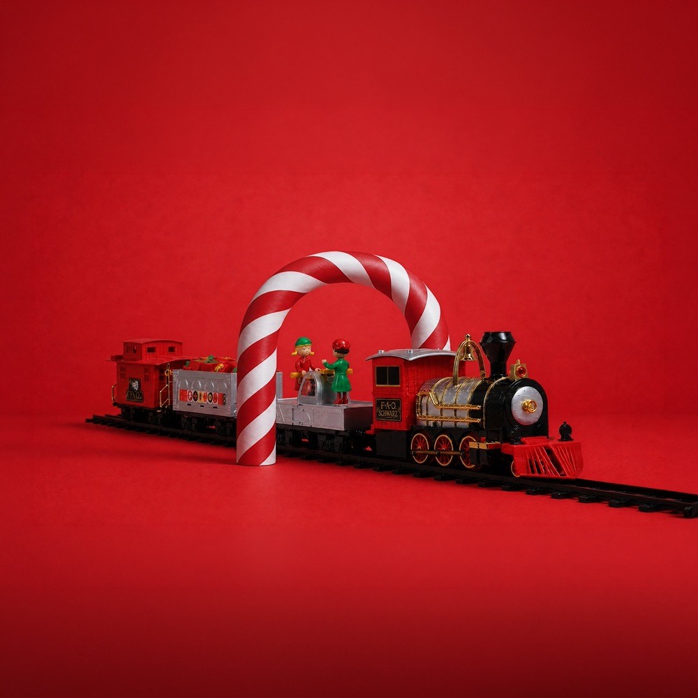 Festive toy train set with candy cane arch, train cars and miniature figures on red background
