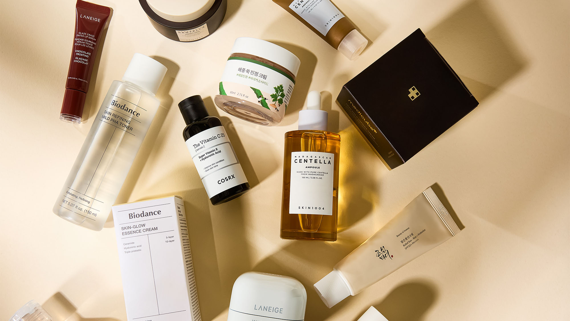 A flat lay of various skincare and cosmetic products on a beige background.