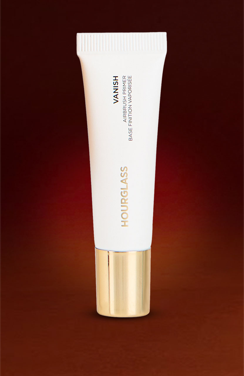 White tube of Hourglass Vanish Airbrush Primer with a gold cap on a dark gradient background.