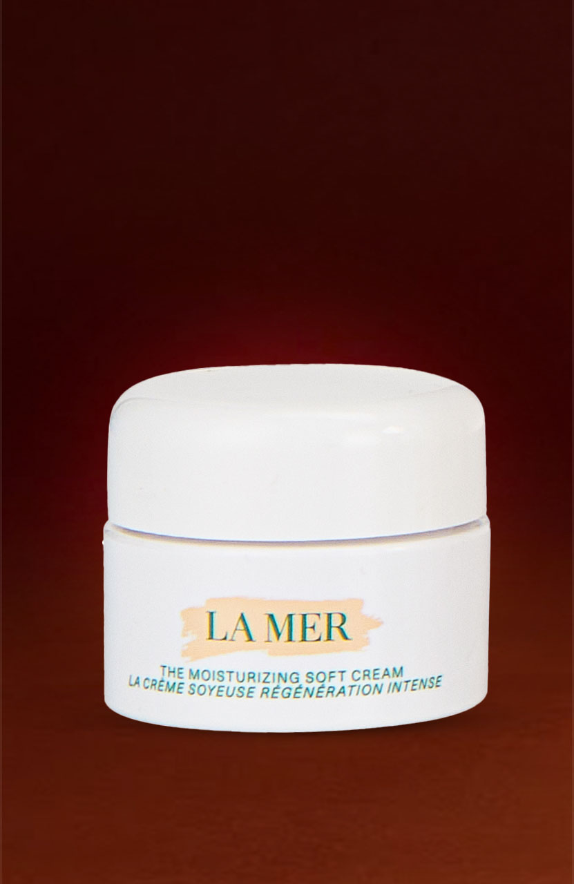 A jar of La Mer Moisturizing Soft Cream on a dark red background.
