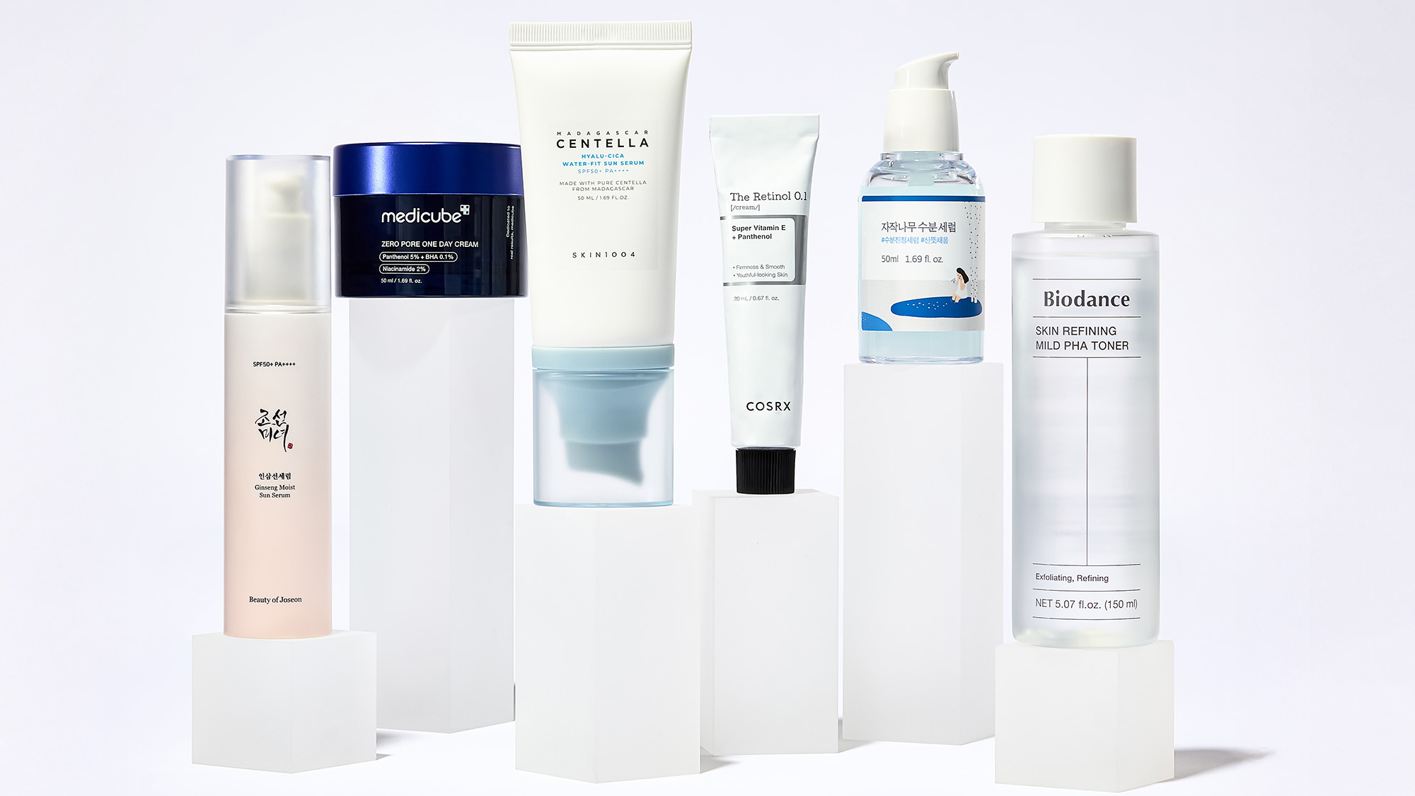 A selection of six skincare products displayed on white platforms, including creams and toners in various containers.