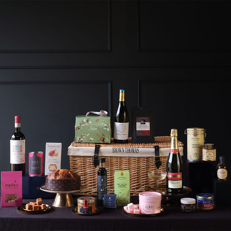 Brown Thomas hamper filled with wine, gourmet treats, and luxury products against a dark background.