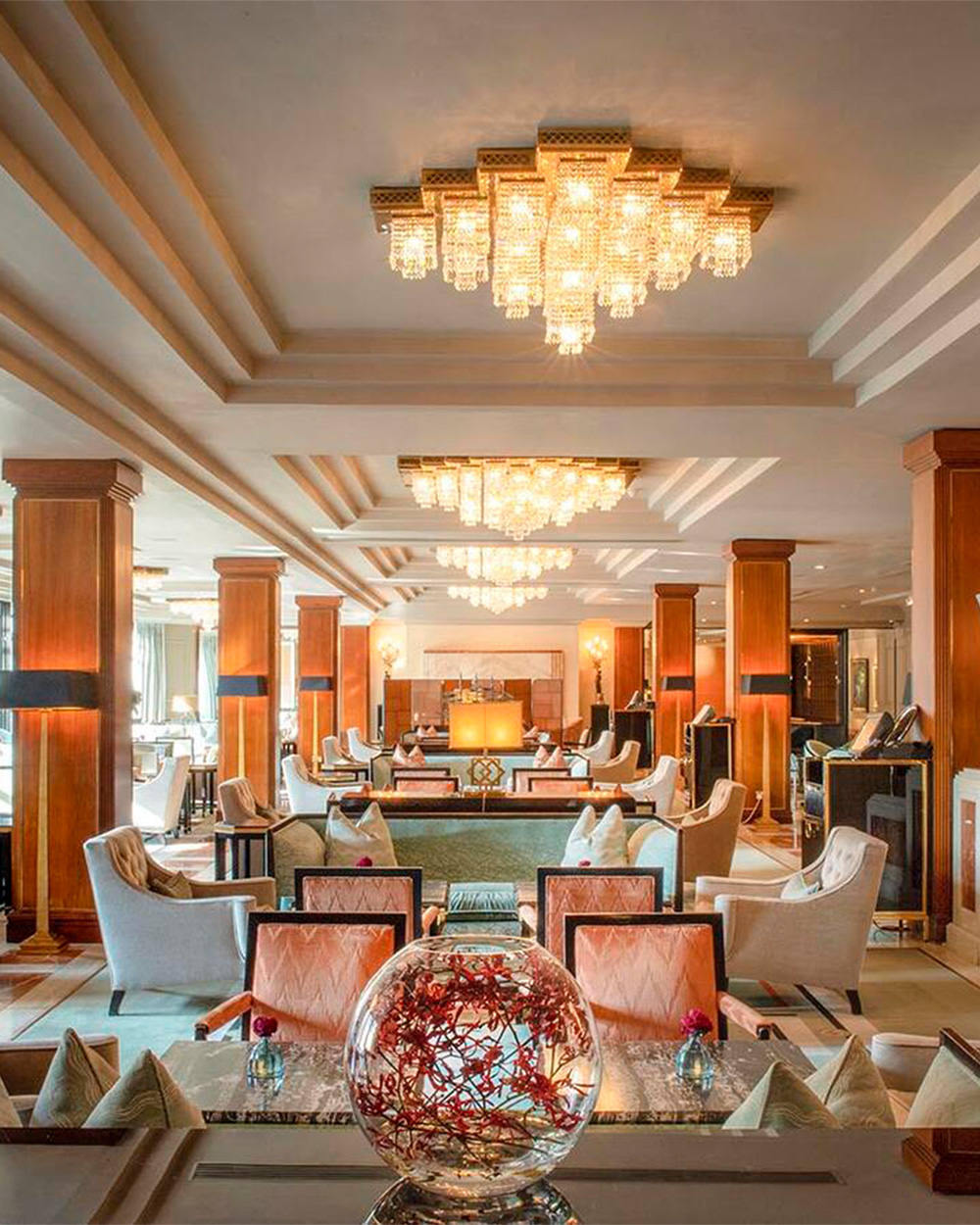 Elegant hotel lobby with plush seating, chandeliers, and warm lighting.