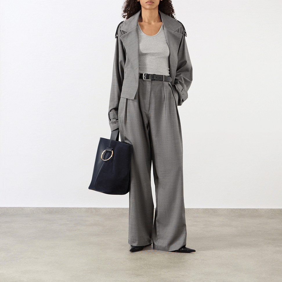 Woman wearing light grey marl hoodie with charcoal wide-leg trousers, demonstrating comfortable layered travel outfit