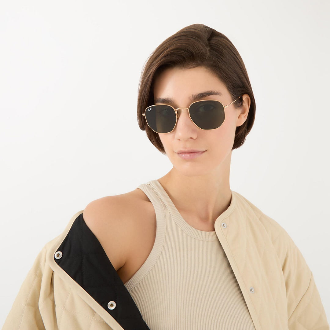 Woman wearing black oval Prada sunglasses and black shirt against neutral background