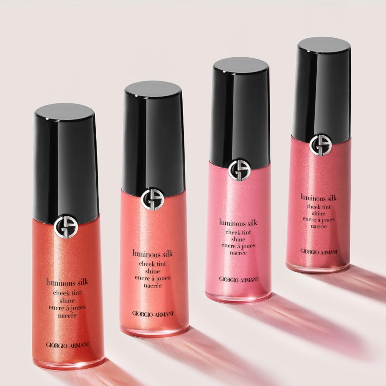 Four Giorgio Armani luminous silk cheek tint shine bottles in graduating shades of coral and pink with black caps
