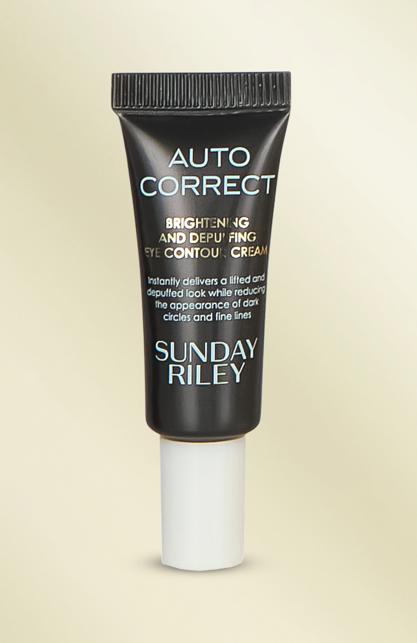 A black tube of 'Auto Correct' eye contour cream by Sunday Riley on a beige background.