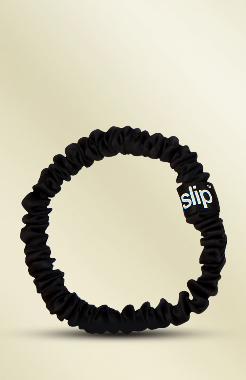 A black, ruffled hair tie with a small tag labeled 'slip' against a light background.