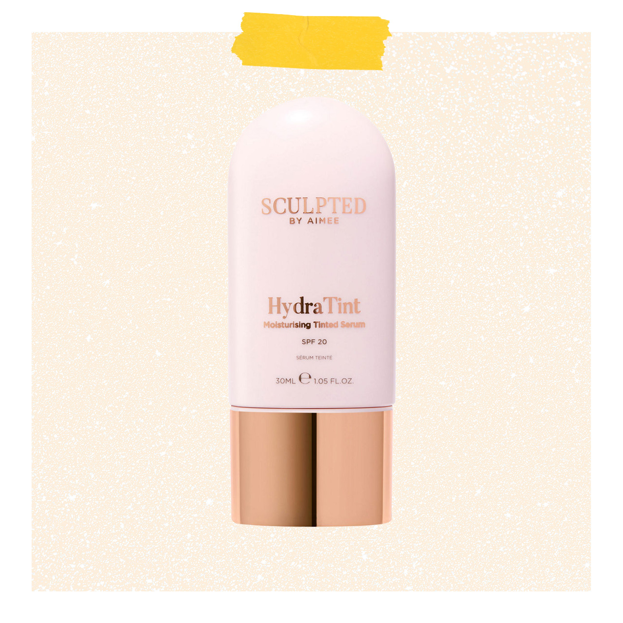 Pink moisturising tinted serum bottle with SPF 20 and rose gold cap on speckled beige background