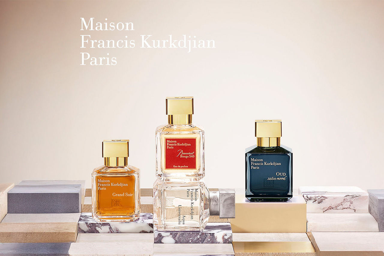 Three Maison Francis Kurkdjian perfume bottles on a marble-patterned surface.