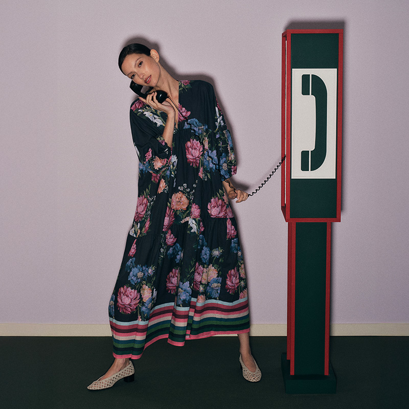 Person in a floral dress using a vintage-style telephone, sitting in a colorful room.
