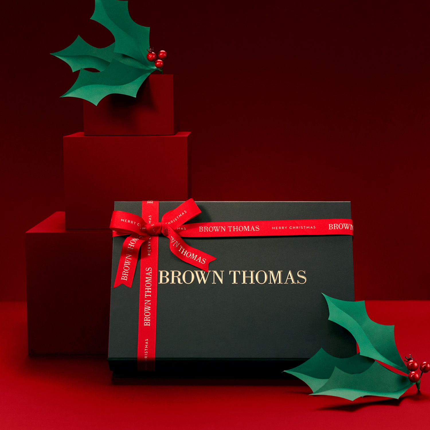 Gift boxes, primarily red and green, with 'Brown Thomas' branding, featuring festive ribbons and holly leaves.