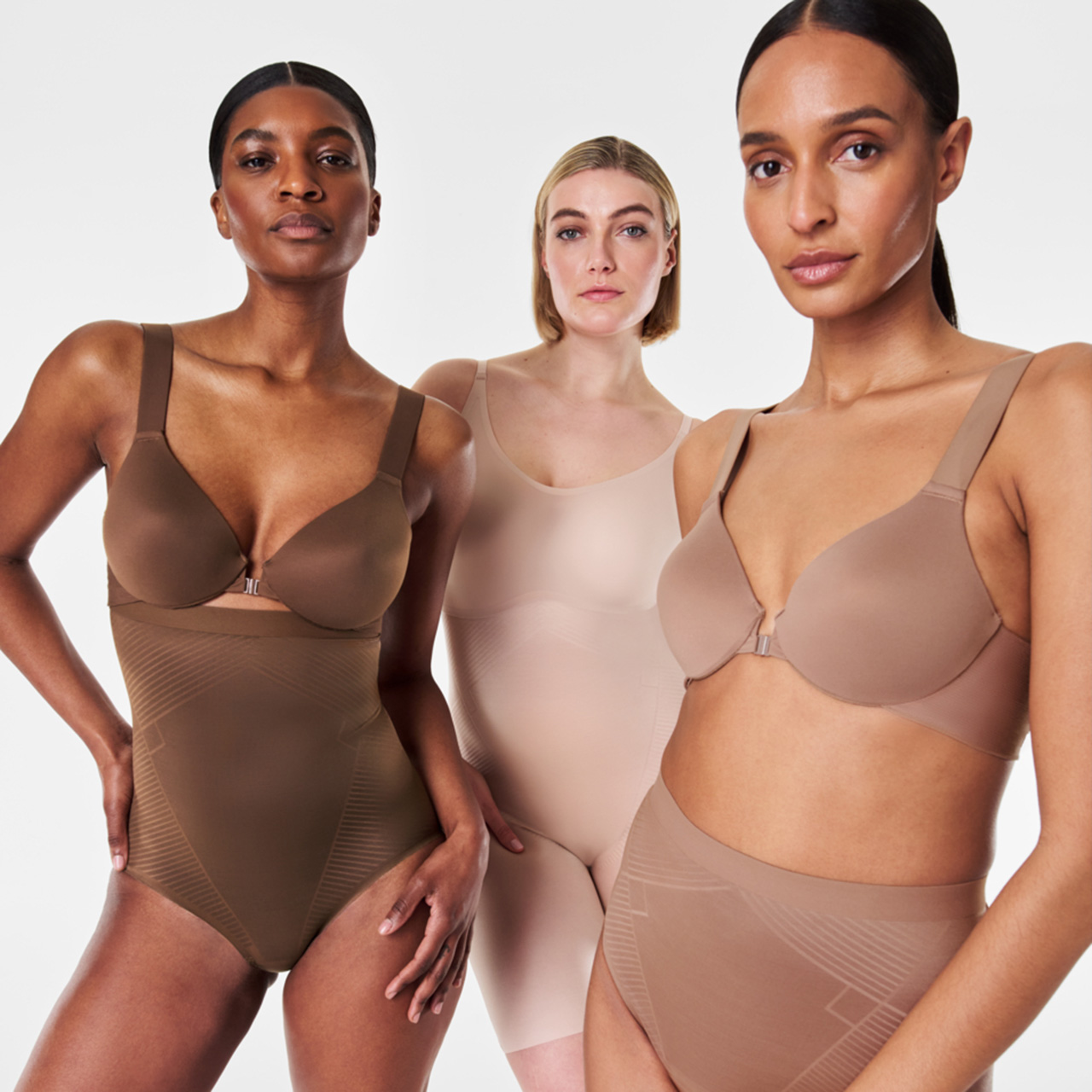 Three women wearing neutral-toned shapewear in different styles and shades