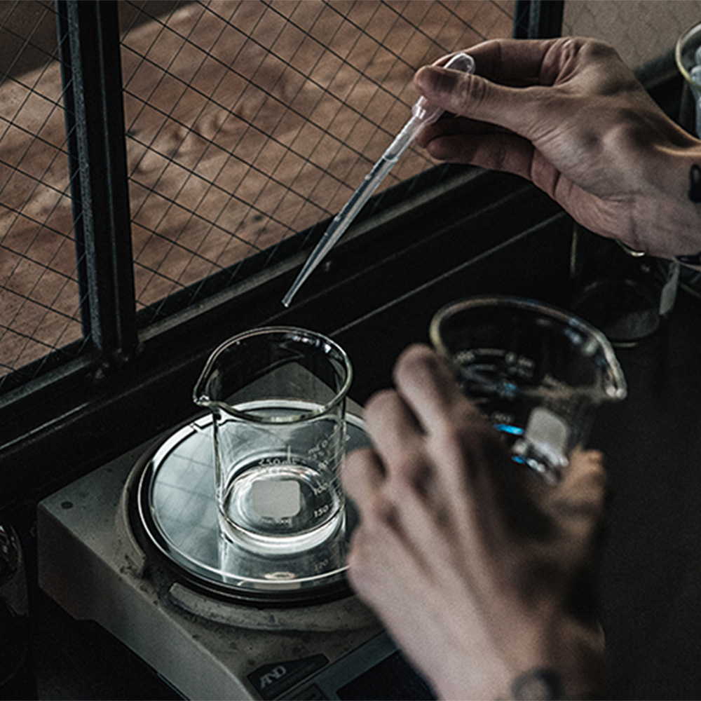 Hands pouring liquid into glass beakers during fragrance preparation demonstration