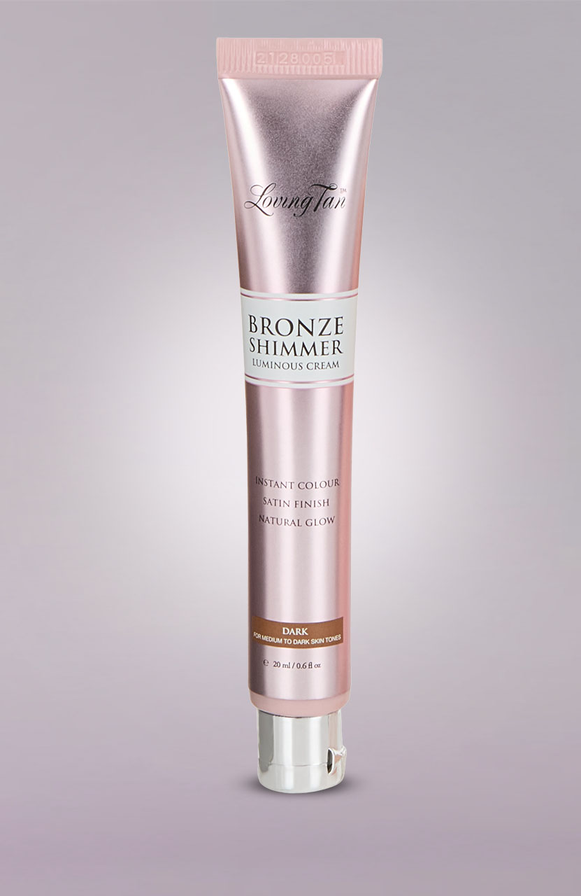 Pink tube of 'Bronze Shimmer Luminous Cream' for a natural glow, with satin finish, labeled 'Dark' for medium to dark skin tones.