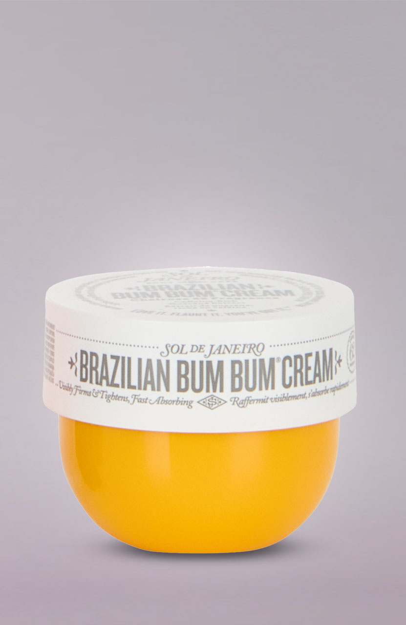 A jar of Sol de Janeiro Brazilian Bum Bum Cream with a white lid and orange container on a light purple background.