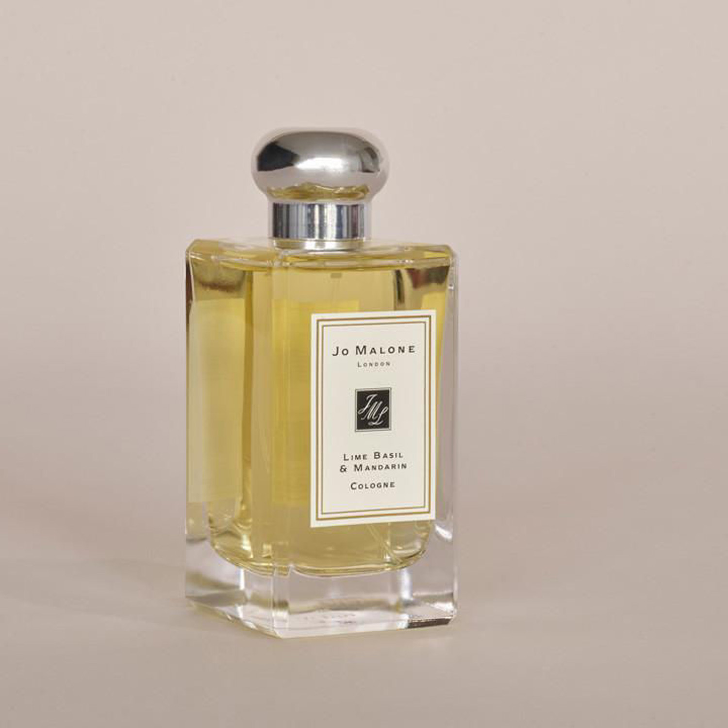 A clear glass perfume bottle with a silver cap, containing yellow liquid, labeled 'Jo Malone.'