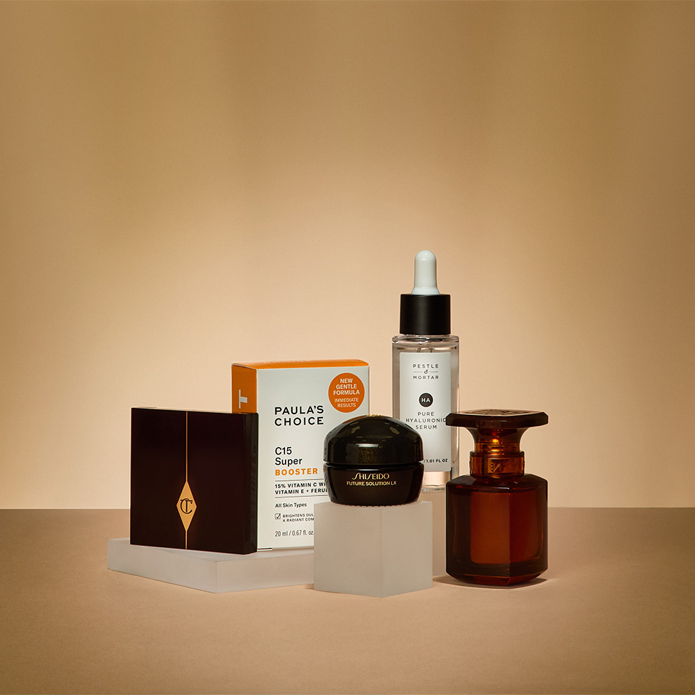 A collection of skincare and cosmetic products arranged on a beige surface.